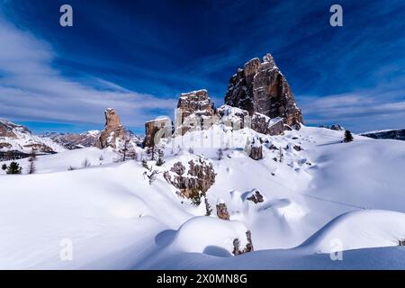 Snowdrift creating artful structures in winter, snow-covered slopes of alpine Dolomite landscape and summits of the Cinque Torri group in the distance Stock Photo