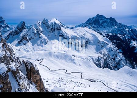 Aerial view on the snow-covered Giau pass from Mt. Nuvolau in winter, the snow-covered summits of Mt. Cernera and Mt. Civetta in the distance. Stock Photo