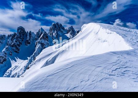 Snowdrift creating artful structures in Tre Cime Natural Park in winter, the summits of Cadini di Misurina in the distance, seen from Monte Campedele. Stock Photo