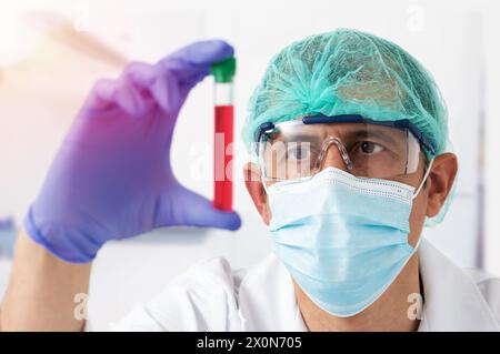 Young woman wearing protective face mask and eyeglasses examining test tube at laboratory with focus on the eyes Stock Photo