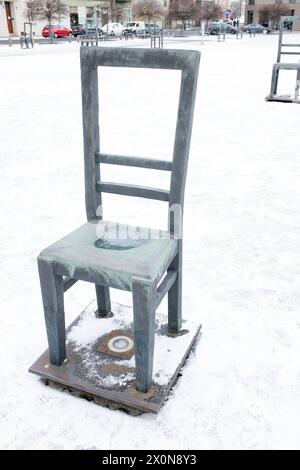 Empty chairs memorial in the snow on Jewish Heroes Square in Krakow, Poland, on the site of Zgody Square in the former Jewish ghetto in World War II Stock Photo