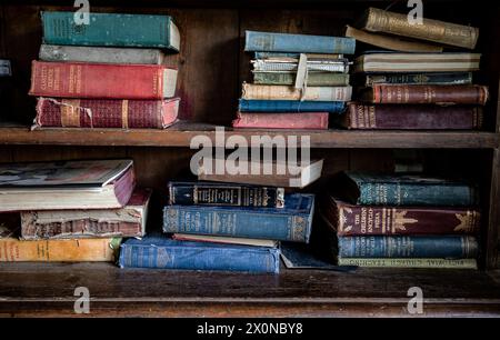 Vintage books on shelf colourful in messy order dusty Stock Photo