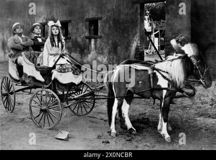 MARY PICKFORD on set candid in late 1919 in costume with set visitors DOUGLAS FAIRBANKS Sr. and CHARLIE CHAPLIN during filming of POLLYANNA 1920 director PAUL POWELL book Eleanor H. Porter play Catherine Chisholm Cushing adaptation Frances Marion Mary Pickford Company / United Artists Stock Photo