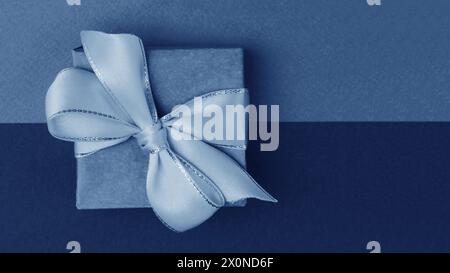 Top view of paper gift box tied with ribbon. Gift box on background separated by two different colors, blue and deep blue.. Christmas, holidays and ce Stock Photo