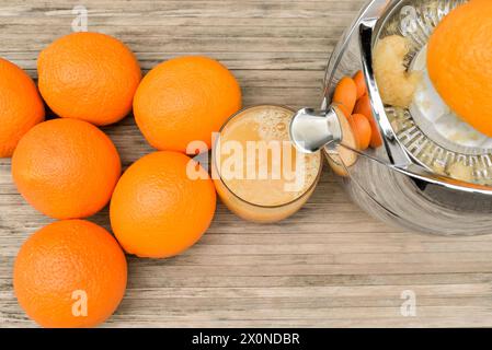 Oranges and glass with orange juice while juicing with citrus juicer Stock Photo