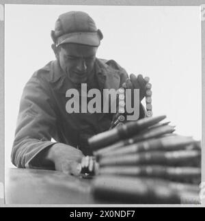 Photographic negative showing RAF, WAAF, and USAAF personnel cooperating at a British station, with Sergeant A. Baker re-arming a Spitfire for a US pilot. Stock Photo