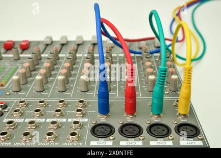 Music mixing console with connected audio jack plugs. Different colors audio cables for connecting and recording music instrument. Stock Photo