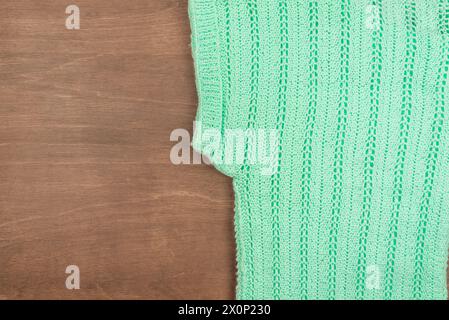 Top view of knitted green wool sweater on wooden background Stock Photo