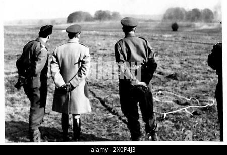 HIS MAJESTY THE KING VISITS INVASION TROOPS - His Majesty watching infantry 'blowing themselves in'. This is a speeded up form of digging in, in which slit trenches are blasted out of the ground with Hawkins Anti-tank mines instead of being dug by spade. Mines are laid in holes about a foot deep and the fuse lighted. The men withdraw while mines explode and then move forward to the trenches which require very little digging to make them complete. Photographic negative , British Army Stock Photo