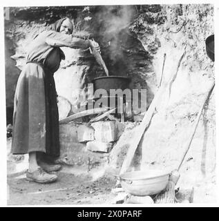 ITALY : EIGHTH ARMYFRONT LINE VILLAGE - An Italian woman cooks foods for the family among the grottoes S. of the town. Photographic negative , British Army Stock Photo