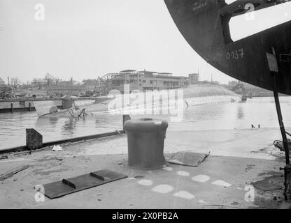 BRITISH NAVY TAKES OVER AT KIEL. 12 MAY 1945, KIEL. THE ROYAL NAVY TRAVELLING OVERLAND FROM OSTEN TOOK OVER THE GERMAN NAVAL PORT AND DOCKYARD AT THE SOUTHERN END OF KIEL BAY. - The ADMIRAL SCHEER, target for RAF bombs, lying bottom-up at Kiel. In the foreground is the pre-fabricated bow piece of a U-boat Stock Photo