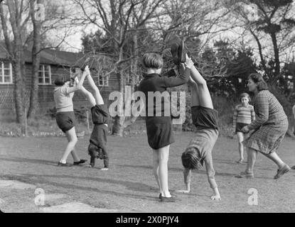 EVACUEES TO A COMMUNAL HOSTEL IN THURLESTONE, SOUTH DEVON, ENGLAND, 1941 - Miss Gabb leads girls of Southville Senior Girls School, Bristol, in a gymnastics exercise at the Swallows Communal Hostel at Thurlestone, Devon. Miss Gabb has been evacuated to Devon with 24 schoolchildren and some of their younger brothers and sisters Stock Photo