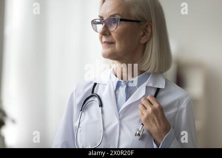 Closeup of proud mature general practitioner looking aside posing indoor Stock Photo