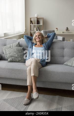 Elderly woman enjoy weekend leaned on cozy sofa Stock Photo