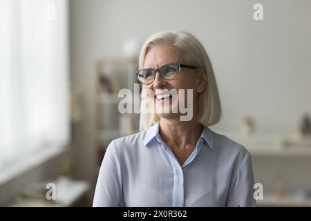 Attractive mature businesslady or teacher laughing standing alone at workplace Stock Photo