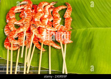 Grilled shrimp skewers on verdant banana leaf with taste of street food's simple yet rich flavors. Healthy, freshly cooked seafood at local market exu Stock Photo