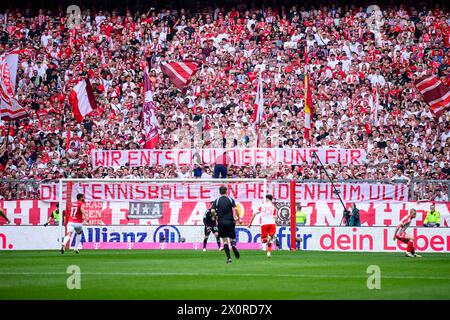 Munich, Germany. 13th Apr, 2024. Soccer: Bundesliga, Bayern Munich - 1. FC Köln, matchday 29, Allianz Arena. FC Bayern Munich fans hold up a poster against Uli Hoeneß with the words 'We apologize for the tennis balls in Heidenheim, Uli!'. Credit: Tom Weller/dpa - IMPORTANT NOTE: In accordance with the regulations of the DFL German Football League and the DFB German Football Association, it is prohibited to utilize or have utilized photographs taken in the stadium and/or of the match in the form of sequential images and/or video-like photo series./dpa/Alamy Live News Stock Photo