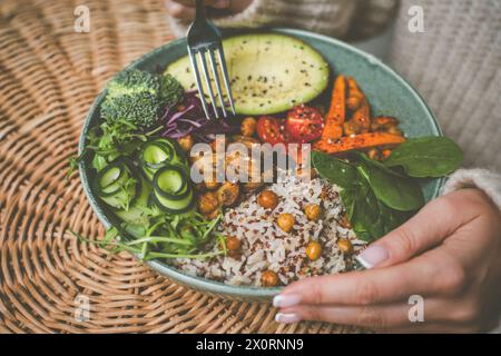 Woman eating healthy buddha bowl. Buddha bowl with rice, quinoa, avocado and vegetables Stock Photo