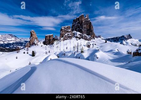 Snowdrift creating artful structures in winter, snow-covered slopes of alpine Dolomite landscape and summits of the Cinque Torri group in the distance Stock Photo