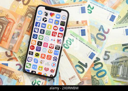 KYIV, UKRAINE - APRIL 1, 2024 Many apps icon on smartphone screen on many euro money bills. iPhone display with app logo with european currency euro banknotes Stock Photo