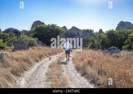 a man walks along a mountain road with a cat on a leash. Travel and Hiking. Stock Photo