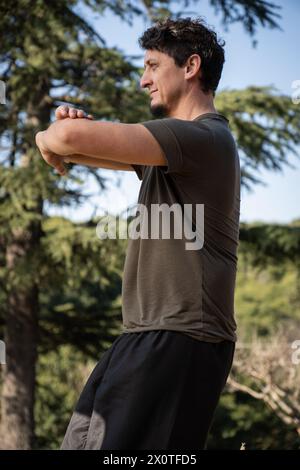 Vertical shot of a mature man practicing Kung Fu, Chinese martial arts, in a natural setting. Stock Photo