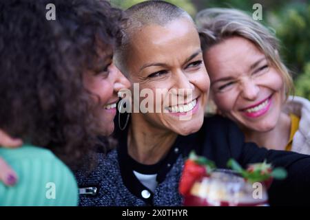 Close up three beautiful smiling middle-aged multicultural women having fun taking selfie outdoor.  Stock Photo