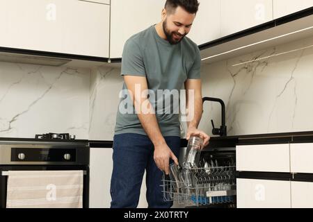 Smiling man loading dishwasher in kitchen, low angle view Stock Photo