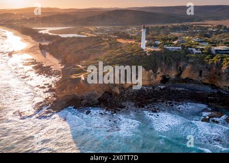 Aerial view of a tall white lighthouse perched on rugged cliffs above the ocean at Aireys Inlet on the Great Ocean Road in Victoria, Australia Stock Photo