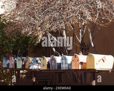 Large tree behind row of many colored mailboxes. Stock Photo