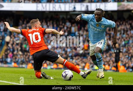 (240414) -- MANCHESTER, April 14, 2024 (Xinhua) -- Manchester City's Jeremy Doku (R) gets past Luton Town's Cauley Woodrow during the English Premier League match between Manchester City and Luton Town in Manchester, Britain, April 13, 2024. (Xinhua) FOR EDITORIAL USE ONLY. NOT FOR SALE FOR MARKETING OR ADVERTISING CAMPAIGNS. NO USE WITH UNAUTHORIZED AUDIO, VIDEO, DATA, FIXTURE LISTS, CLUB/LEAGUE LOGOS OR 'LIVE' SERVICES. ONLINE IN-MATCH USE LIMITED TO 45 IMAGES, NO VIDEO EMULATION. NO USE IN BETTING, GAMES OR SINGLE CLUB/LEAGUE/PLAYER PUBLICATIONS. Stock Photo