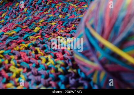 Ball of multi coloured wool on a crocheted blanket with depth of field Stock Photo