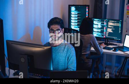 asian and Indian Developer  devops team working  about coding promgram with software computer at night in office Stock Photo