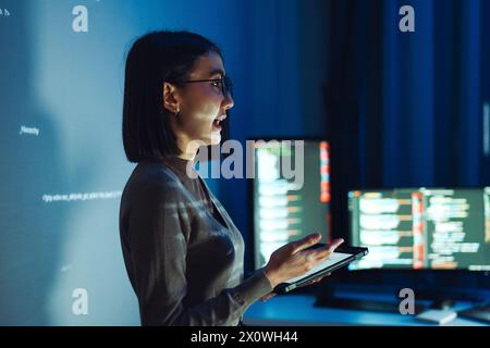 asian woman developer presentation about coding software data with devops team at night in office Stock Photo