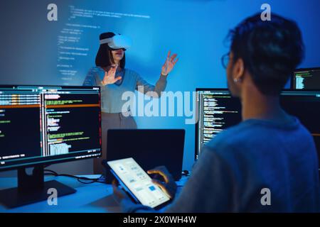 asian and Indian developer devops team testing  virtual reality coding and presentation  with ai prompt  at night in office Stock Photo