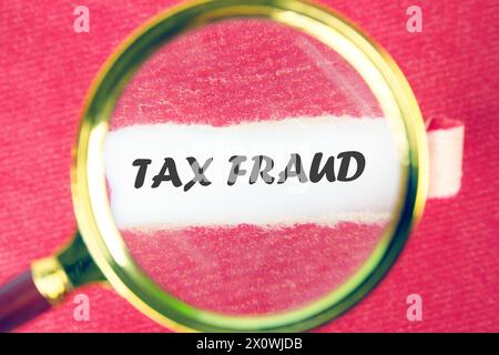 TAX FRAUD through a magnifying glass under a torn piece of paper Stock Photo