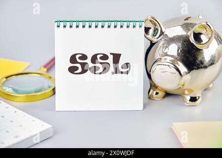 SSL Secure Sockets Layer on a white notebook on a gray background near a piggy bank, a calculator and stickers Stock Photo