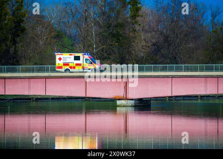 An ambulance belonging to the Bavarian Red Cross drives over a bridge with its emergency lights flashing. Stock Photo