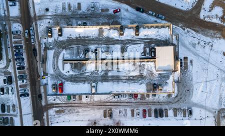 Drone photography of top down view of multistory parking lot with a few cars and covered by snow during sunny winter day Stock Photo