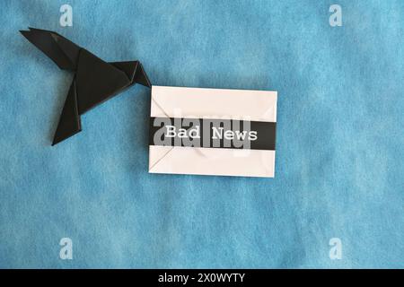 lack raven paper origami carrying white envelope letter with word Bad News. Deliver and bearer of bad news concept. Stock Photo