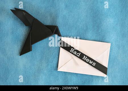 lack raven paper origami carrying white envelope letter with word Bad News. Deliver and bearer of bad news concept. Stock Photo