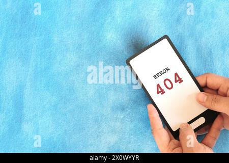 Hand holding a mobile phone with Error 404 or page not found display notice. Stock Photo
