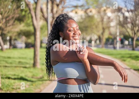 Attractive young woman warming up, stretching her arms before morning workout. Fitness, sport and healthy lifestyle concept Stock Photo