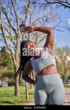 Front view of fit young woman stretching her arms outdoors. Woman doing warmup exercise in the morning. Stock Photo