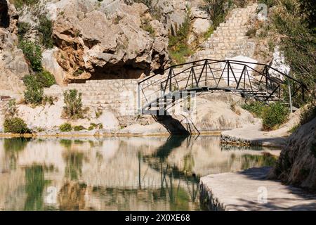 Wrought iron bridge in natural pool of the municipality of Bolbaite with reflections in the water, Spain Stock Photo
