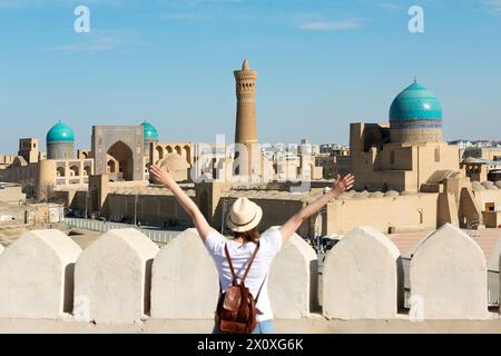 Panoramic view of Bukhara, young woman tourist with arms raised in front of Bukhara city - Uzbekistan Stock Photo