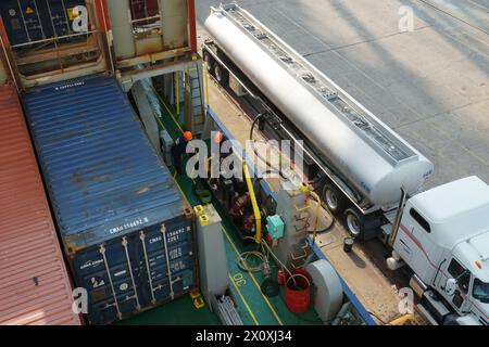 View on fuel hose from tanker truck connected to container vessel in bunker station with valves and manifolds. Stock Photo