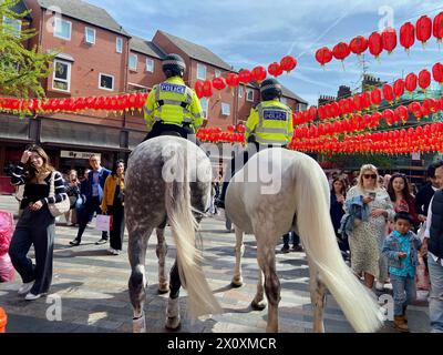 two mounted Met police officers riding horses through chinatown soho ...