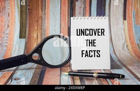 Uncover the facts with text on a notepad, near a magnifying glass and pen on a vintage background Stock Photo