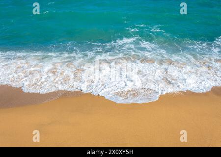 A frothy blue ocean wave on a clean sandy sea beach. Stock Photo
